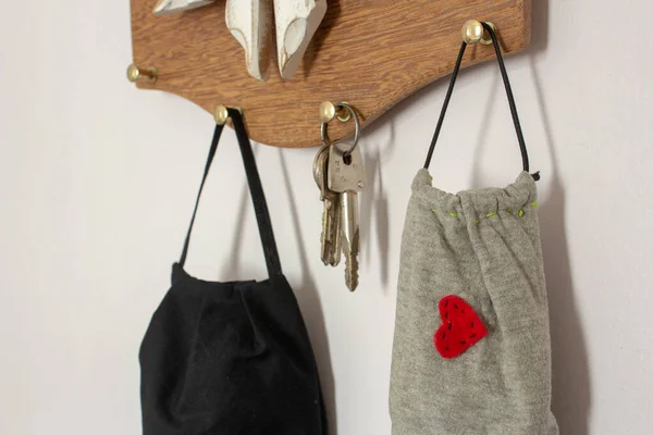 Masks hanging on the wall next to keys, as a new daily item to use because COVID-19