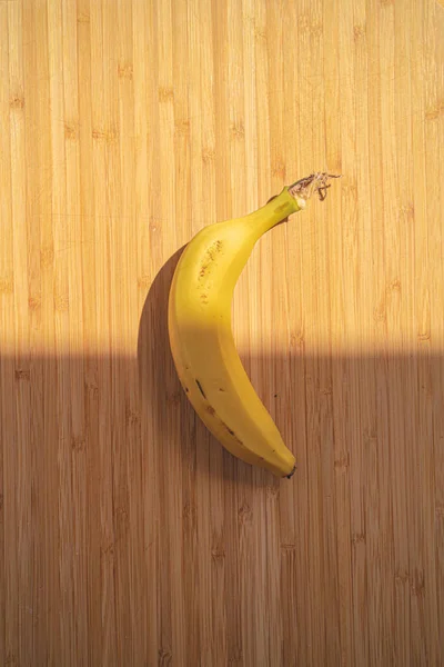 Płaskie Ułożenie Pionowe Zdjęcie Banana Umieszczonego Drewnianej Powierzchni Gdzie Światło — Zdjęcie stockowe