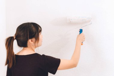 Duvarı boyayan kadın. Roller kullanan profesyonel ressam kız.