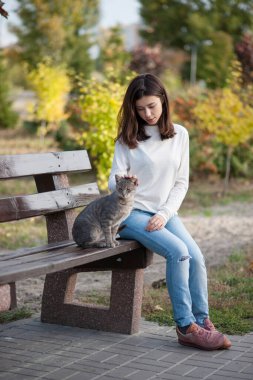 Güzel esmer kız sonbahar parkında bankta oturuyor.