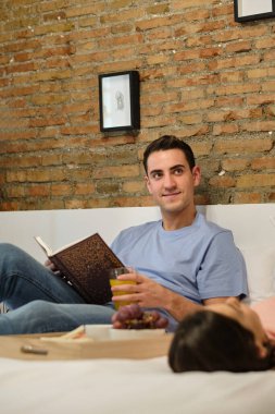 Genç çift evde yatarken kahvaltı yapıyor ve dinleniyor..