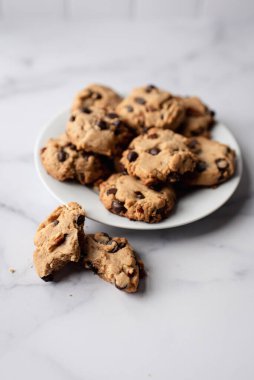 Beyaz mermer tezgahta çikolatalı kurabiyelerin olduğu tabağı kapat..