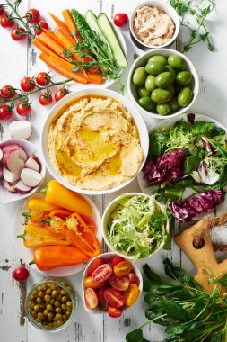 Humus sosu ve çiğ vejetaryen atıştırmalıkları beyaz ahşap masada..                              