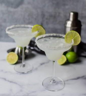 Beyaz mermer tezgahta limonlu iki margarita kokteyli.