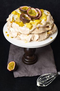 Tutku meyveli Pavlova keki, mango, limon ve muz kreması koyu arkaplanda.