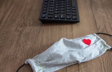 Günlük kullanılacak yeni bir öge olarak, masanın üstündeki bir ofis klavyesinin yanındaki maskeyi kullan, çünkü COVID-19