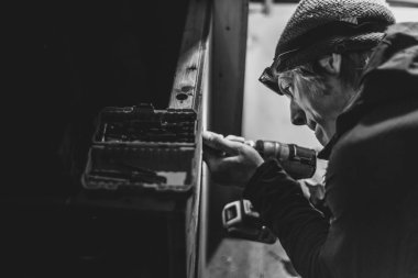 B & W İnsan 'ın yakın plan farı ile düşük ışıkta ahşabı delmesi