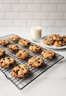 Taze pişmiş çikolatalı kurabiye ve beyaz mermer tezgahta süt..
