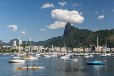 Kayak yapan adama güzel bir manzara, kenetlenmiş yelkenli tekneleri ve kurtarıcı İsa ile Corcovado Dağı, Rio de Janeiro, Brezilya