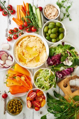 Beyaz ahşap masada iki soslu ve çiğ vejetaryen atıştırmalıkları.                              