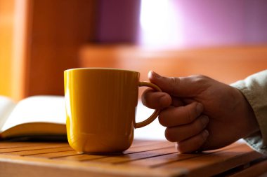 El, evden sarı bir fincan kahve alıyor. Yatak konseptinde kahve..