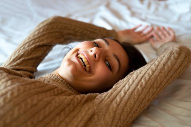 Yatakta gülümseyen bir kadın. Ev kavramında mutluluk.