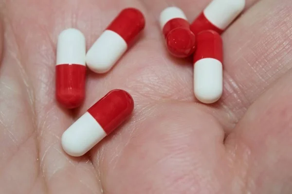 Λευκά Και Κόκκινα Καψάκια Μακροσκοπική Προβολή Στα Χέρια — Φωτογραφία Αρχείου