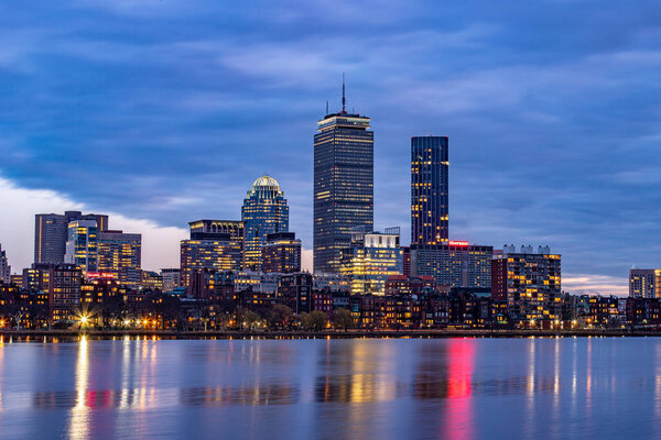 Blue hour cityscape buildings reflecting in water.