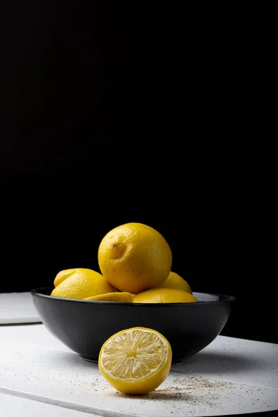 Gelbe Zitronen Einer Schwarzen Schüssel Auf Einem Weißen Holztisch — Stockfoto