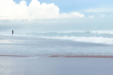 girl in profile on the beach with many clouds in the background