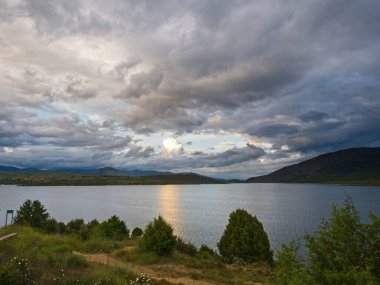 Ufukta dağlar ve bitki örtüsü olan göl, bulutlu gökyüzü Altazar, Madrid, Esspaa 'da bir fırtınayı tehdit ediyor. 