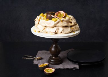 Tutku meyveli Pavlova keki, mango, limon ve muz kreması koyu arkaplanda.
