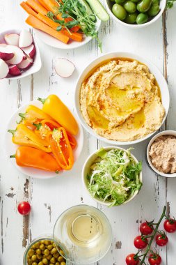 Humus sosu ve çiğ vejetaryen atıştırmalıkları beyaz ahşap masada..                              