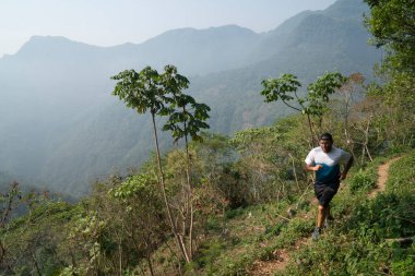 Bir adam Xicotepec dağlarında yüksek bir patikada koşuyor.