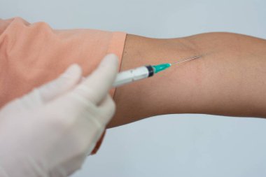 Doktor bir hastanın kolunda şırınga kullanıyor.