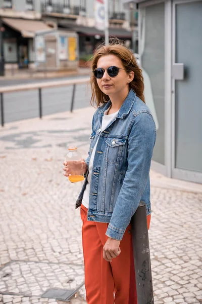 Mulher Uma Jaqueta Uma Rua Com Suco Laranja Uma Garrafa — Fotografia de Stock