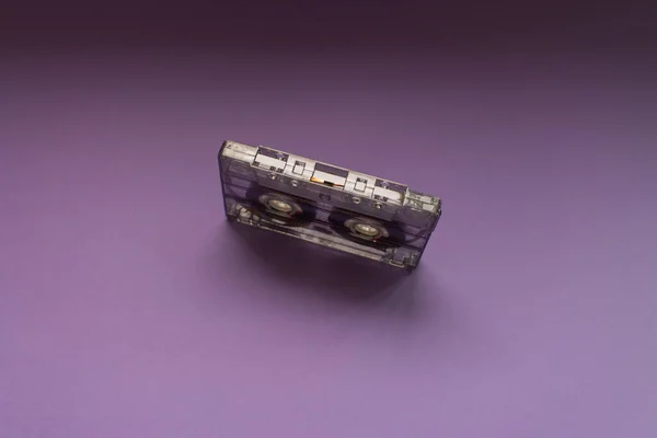 Retro audio tape cassette from 80s and 90s isolated on purple background. Old technology concept. Flat lay, top view with copy space.