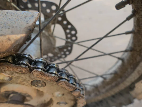 Close up dirty motorcycle chain and sproket on enduro bike.