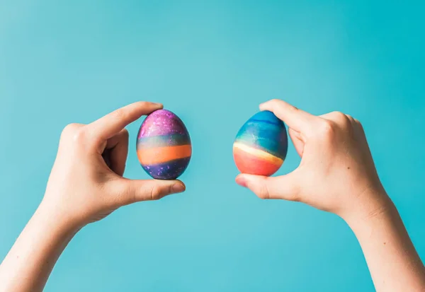 Hands Holding Two Brightly Colored Easter Eggs Blue Backdrop — Foto Stock