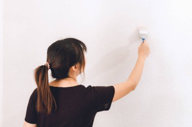 Duvarı boyamak için boya fırçası kullanan Asyalı kadın.