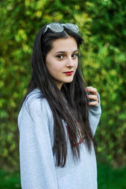 Güzel kız arka plandaki yeşil bambu yapraklarına bakıyor.