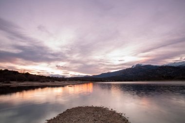 Manzanares del Real, Madrid, İspanya 'da gün batımında Santillana rezervuarında küçük bir ada.