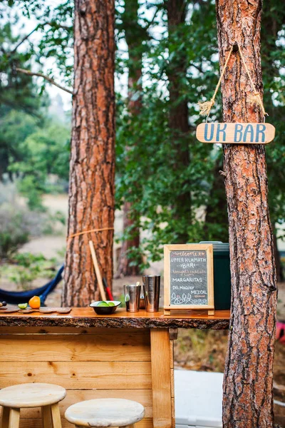 Outdoor mini bar between pine trees with two stools