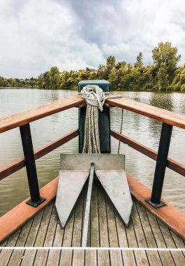 Ormanla çevrili nehirde yol alan ahşap bir teknenin pruvası.