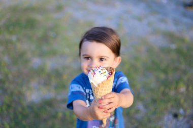 Küçük bir çocuk elinde bir dondurma külahını tutuyor.
