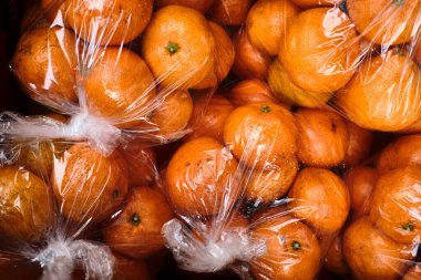 Yerel bir markette plastiğe sarılı taze organik portakallar.