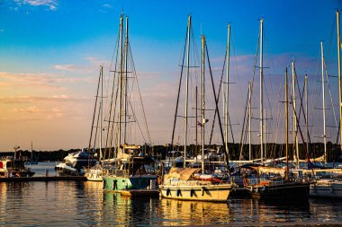 Arka planda bulutlar olan küçük ranzada direkli tekneler.