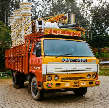 Hindistan 'ın Doğu Ghat Dağları' ndaki Yercaud, Tamil Nadu 'da bir düğün yapımı için sarı iş kamyonunda ya da kamyon taşıma sütunlarında iki Hintli oturup bekliyor.