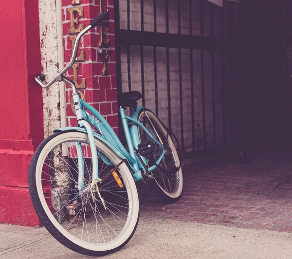 路地の近くの明るい赤い壁にもたれているターコイズブルーの自転車 — ストック写真