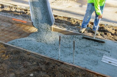İnşaat müteahhiti kaldırım için şamandıra kullanırken beton alçıya alan işçiler.