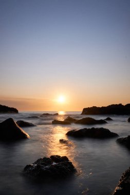 Atlantik Okyanusu 'nun arka planında günbatımı olan kayanın üzerindeki güneş patlaması, Punta Ballena, Maldonado, Uruguay