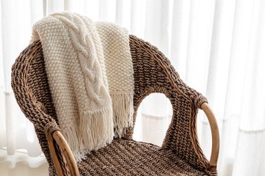 Sandalyenin üzerine yün örülmüş ekose kumaşlar örülmüş.