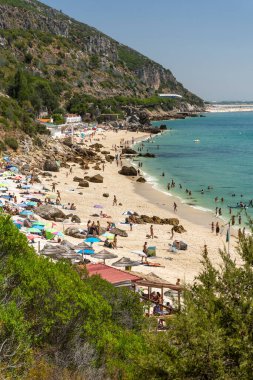 Setubal, Lizbon, Portekiz yakınlarında güneşli bir günde turist ve şemsiyelerle sahile güzel bir manzara