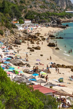 Setubal, Lizbon, Portekiz yakınlarında güneşli bir günde turist ve şemsiyelerle sahile güzel bir manzara