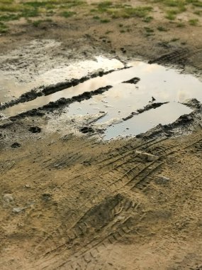 Yağmurlu günlerde su birikintileri. Çamurlu arazi, yağmurdan sonra toprak yol. Lastik izi olan çamur ve su birikintisi. Yolların Dayanıklılığı. Çaresizlik kavramı