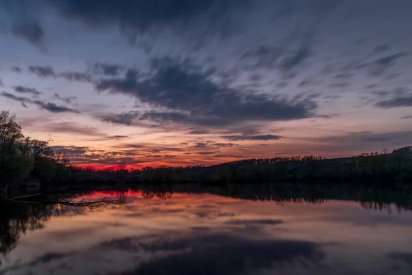 暗い雲とオレンジの赤の輝きを反射して池の上にテーマの夕日 — ストック写真