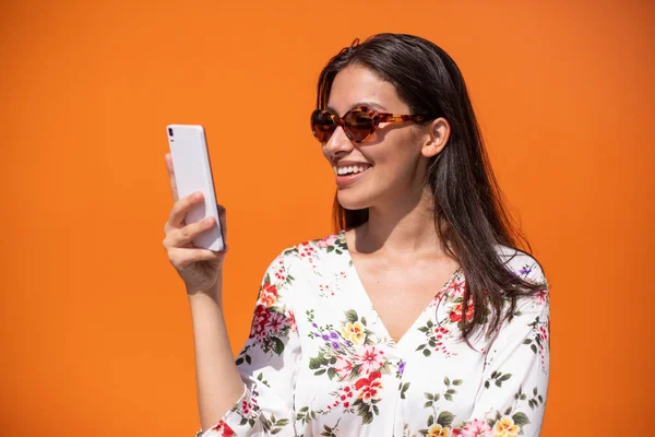 一位年轻的女执行官正在用橙色背景的手机阅读一条信息 — 图库照片
