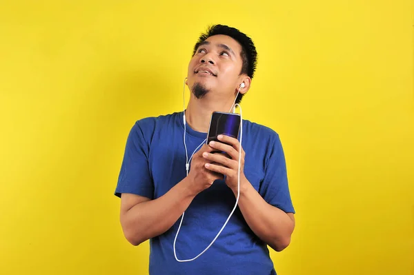 Sıradan Mavi Tişörtlü Asyalı Adam Kulaklık Takıyor Akıllı Telefondan Müzik — Stok fotoğraf