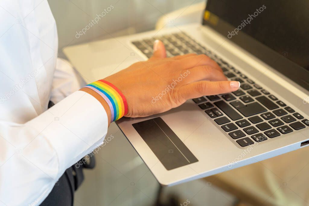 woman's hand with lgtbi bracelet working from her laptop