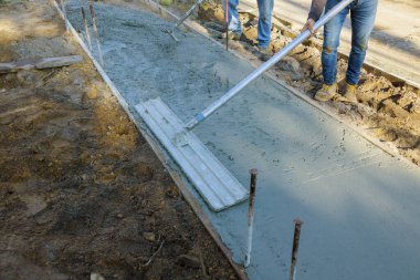 İnşaat müteahhiti kaldırım için şamandıra kullanırken beton alçıya alan işçiler.